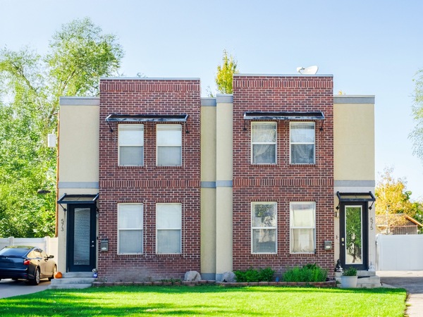 Front view of a symmetrical two-story duplex with two entrances and rectangular windows with awnings.